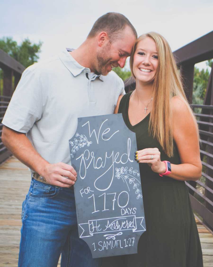 Husband and wife who battled fertility issues hold up sign saying, "we prayed for 1170 days he answered"