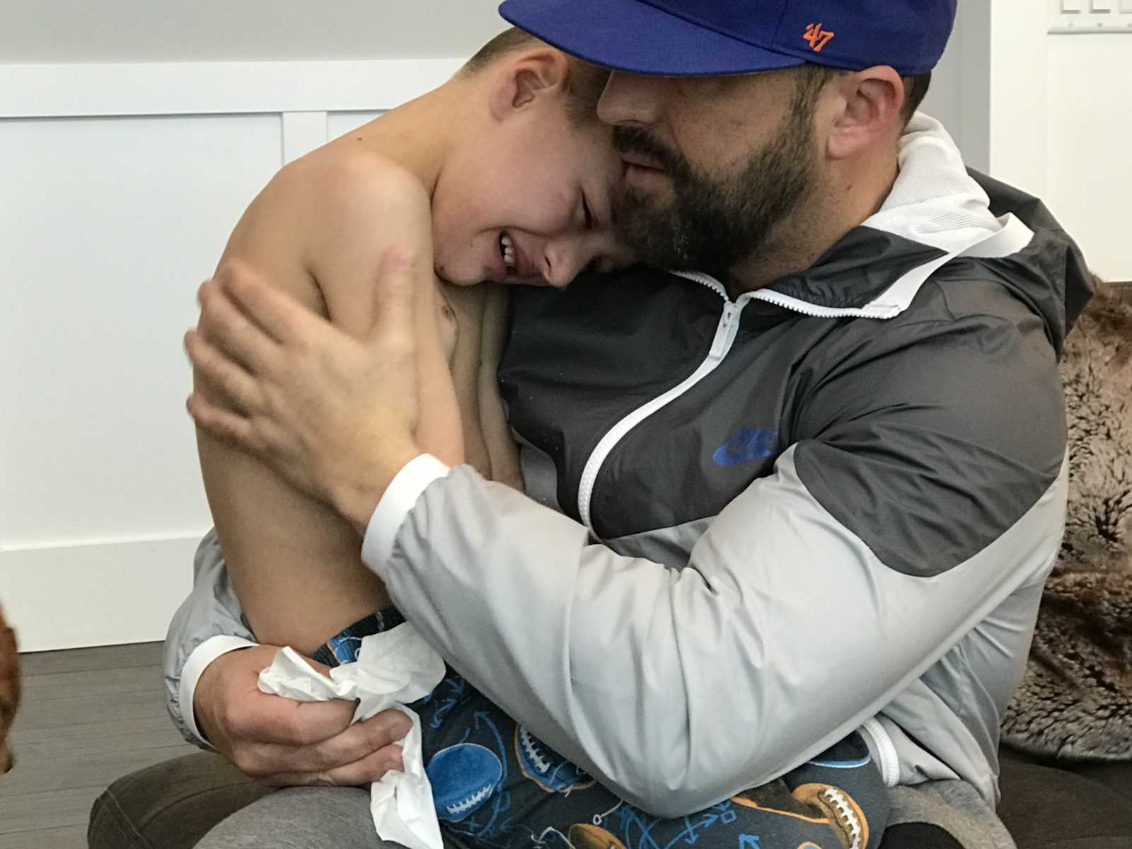 Little boy with leg tumors crying in dad's lap
