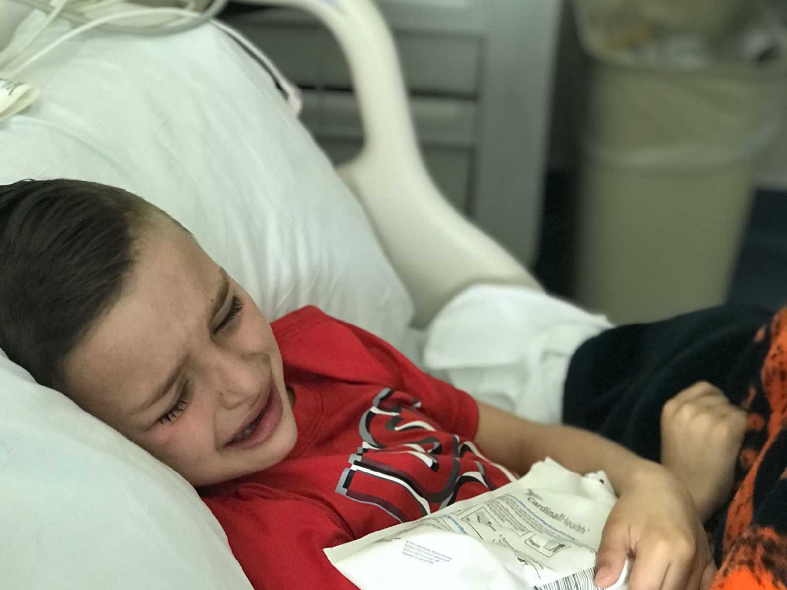 Little boy with leg tumors crying in hospital bed 