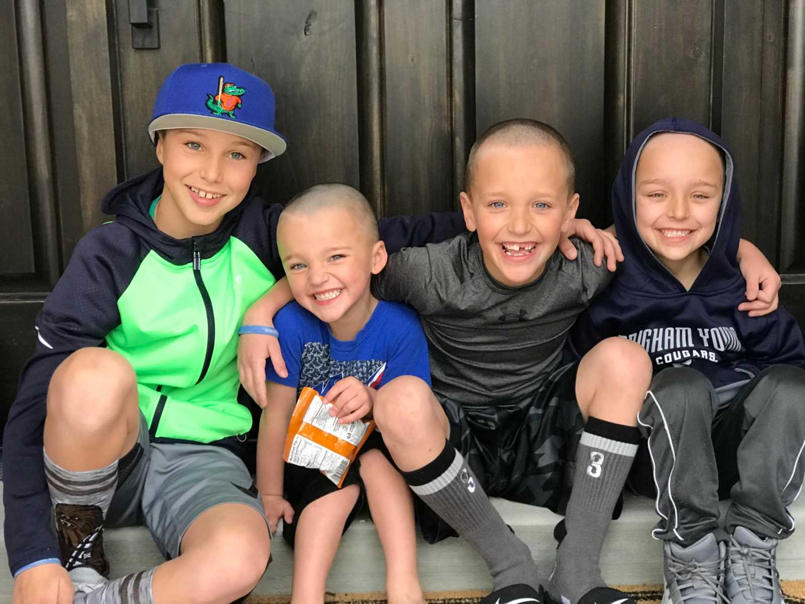 Boy who will have leg tumors later in life sitting with three brothers 