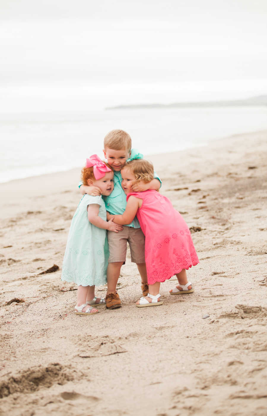 Brother wraps arms around little sisters, one of which had open heart surgery 