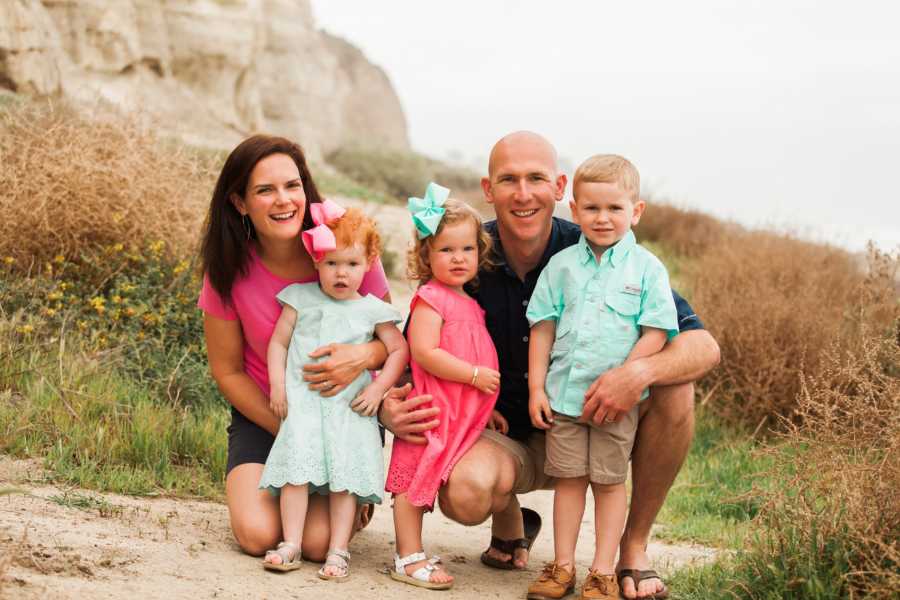 Mother and father kneel next to son and two daughter's one of which had open heart surgery