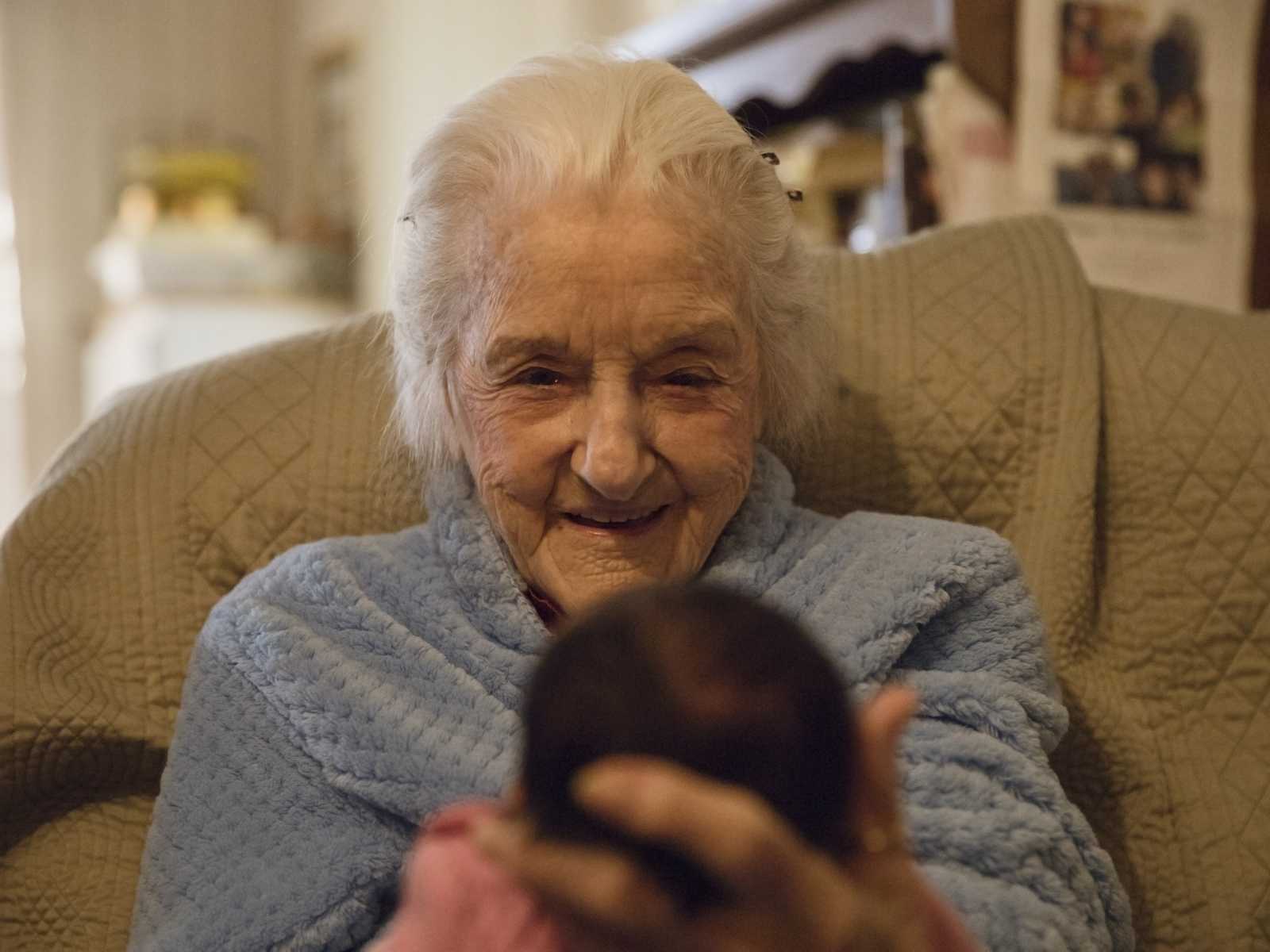 92 year old woman smiles as she sits holding a newborn who is her namesake