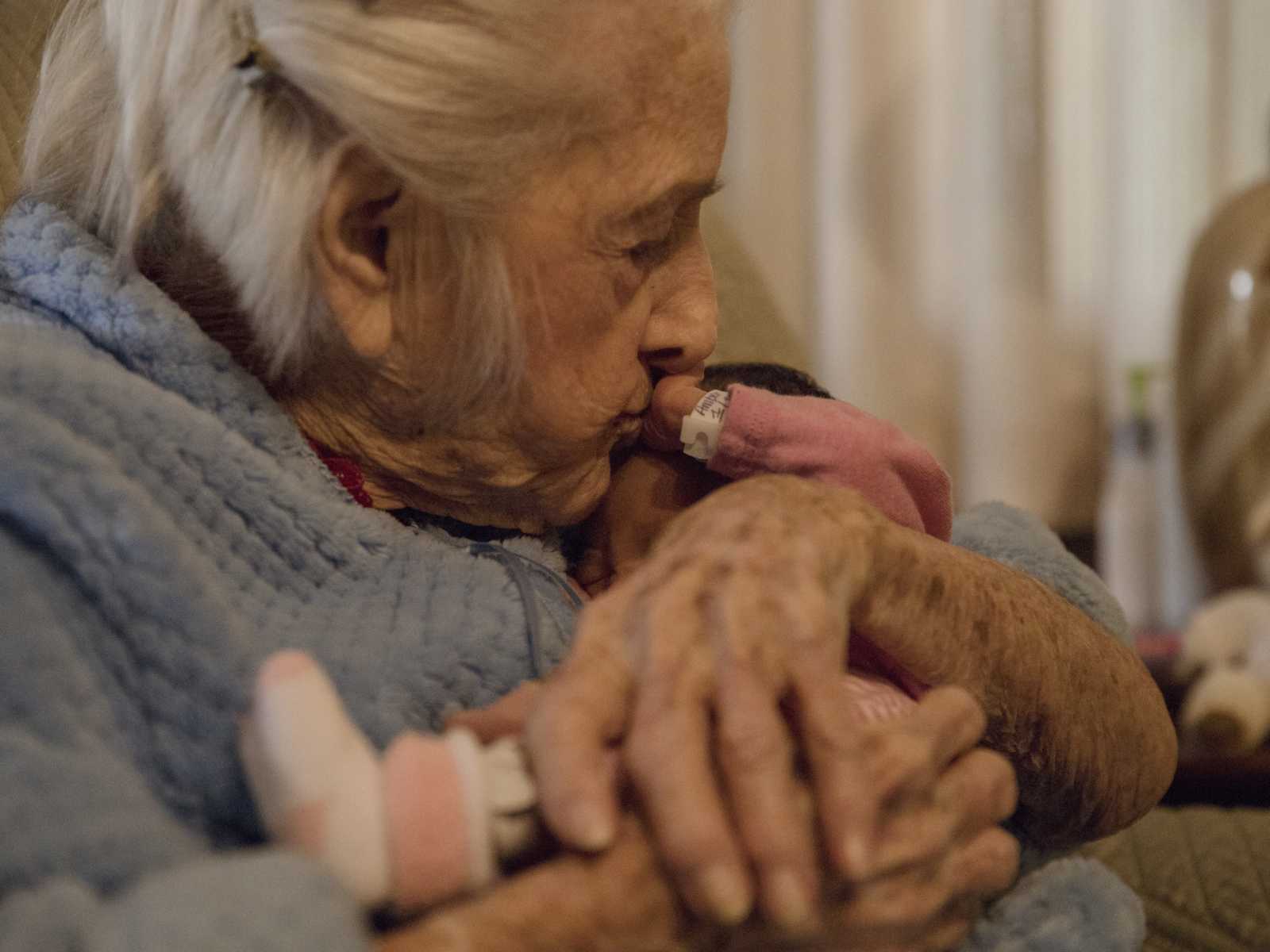 Close up of 92 year old woman kissing newborn on the head who is her namesake