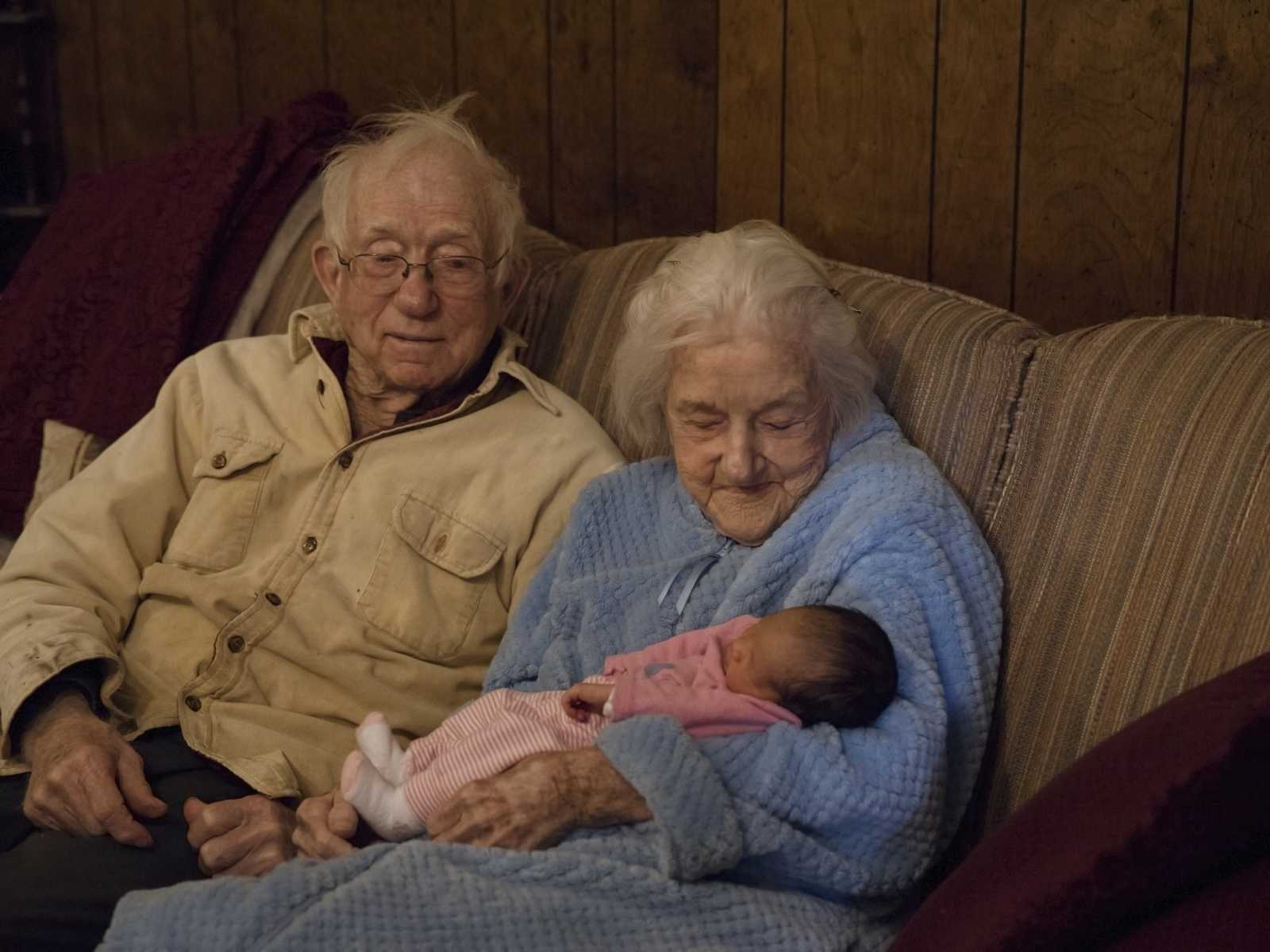 92 year old woman sits on couch holding newborn who is her namesake next to her husband