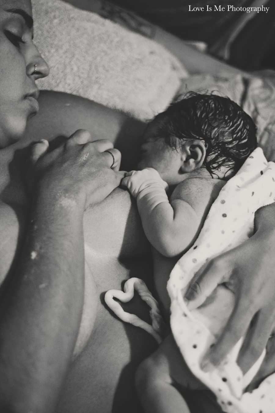 Woman who had water birth looks down at newborn as she breastfeeds