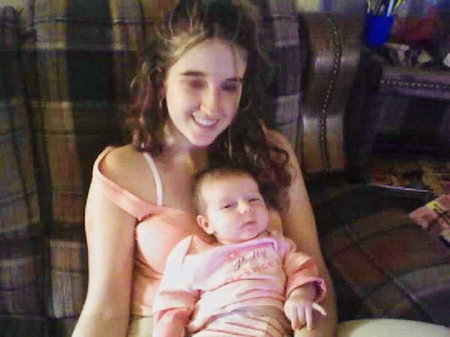 Teen mother with Crohn's Disease sitting in chair with baby daughter in her lap