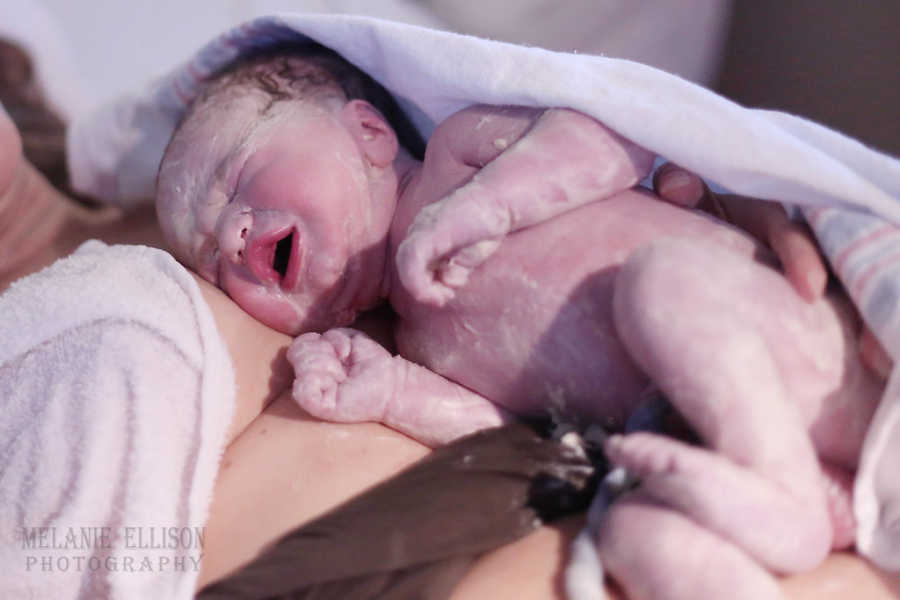Newborn baby lies on mother's bare chest