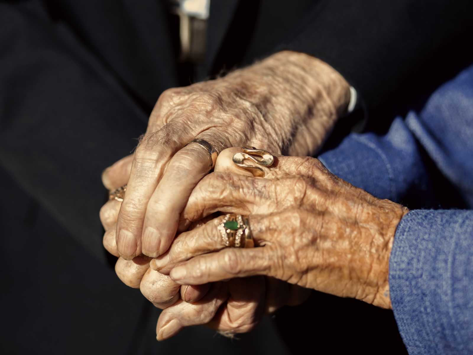 Close up of 92 year old woman and husband holding hands with their wedding rings on