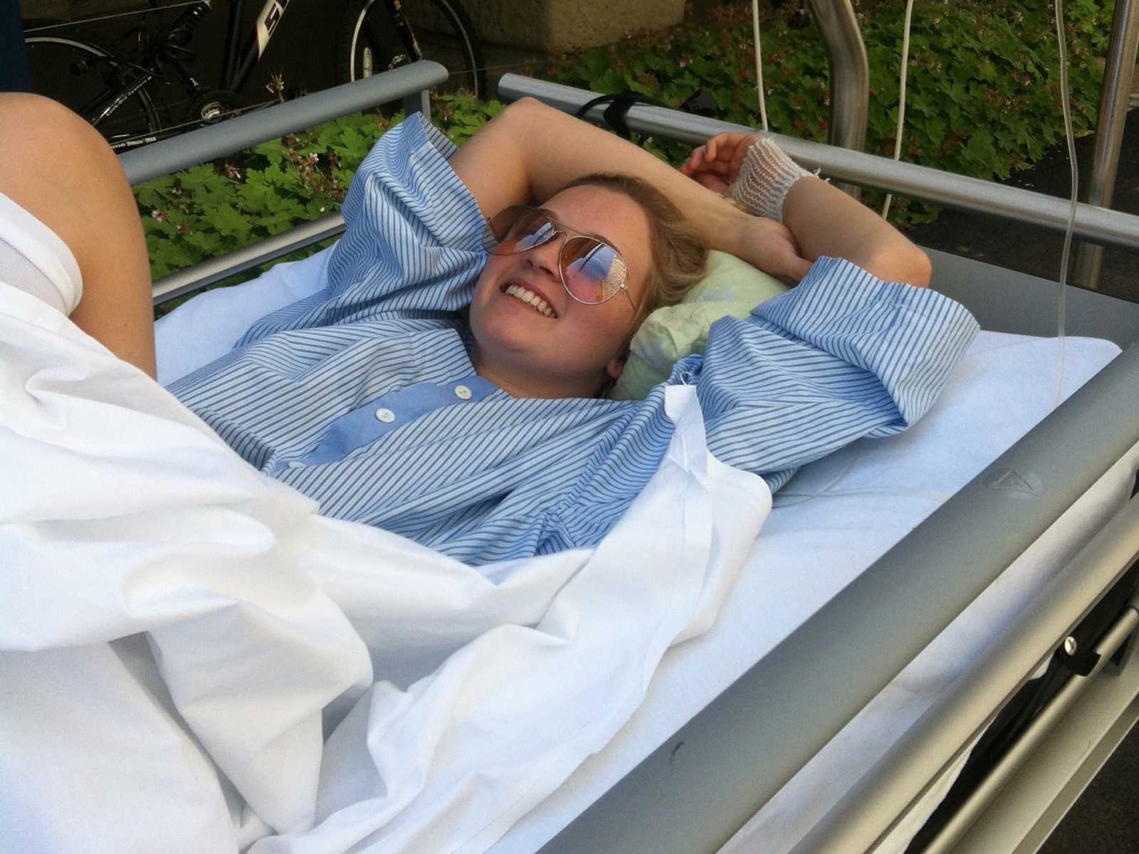 Woman with spine injury lying in hospital bed smiling