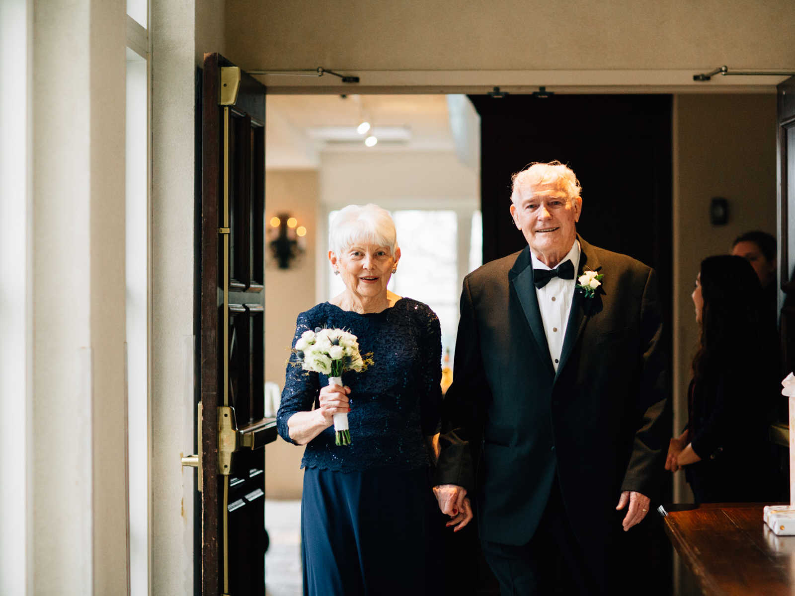 Elderly bride and groom smile hand in hand after wedding