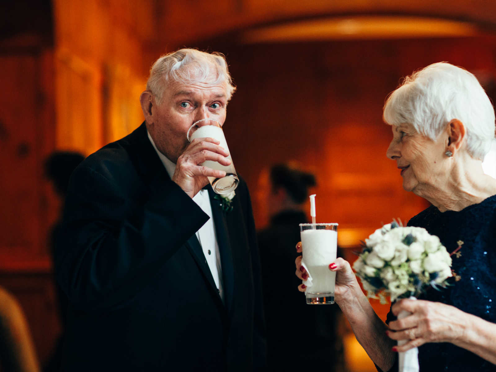 Elderly bride and groom drink frozen margaritas at wedding reception