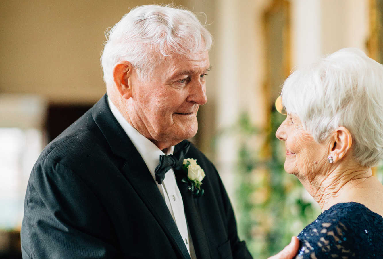 83 year old groom smiles while looking into 77 year old bride's eyes