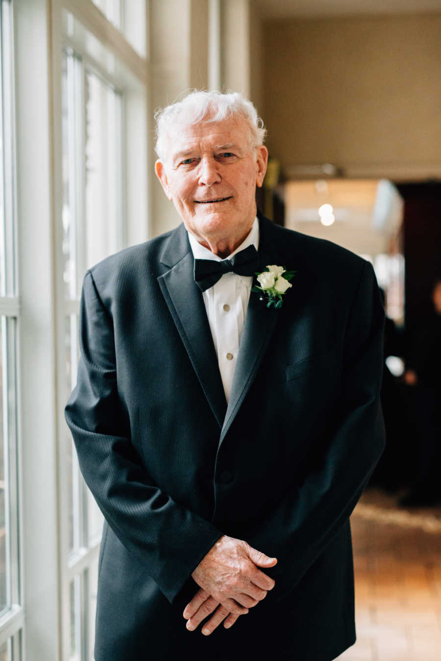 Elderly widow stands in suit smiling before wedding