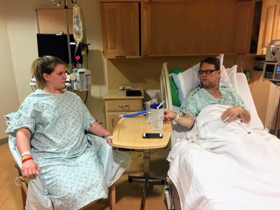 Daughter sitting in chair next to father in hospital bed after kidney transplant