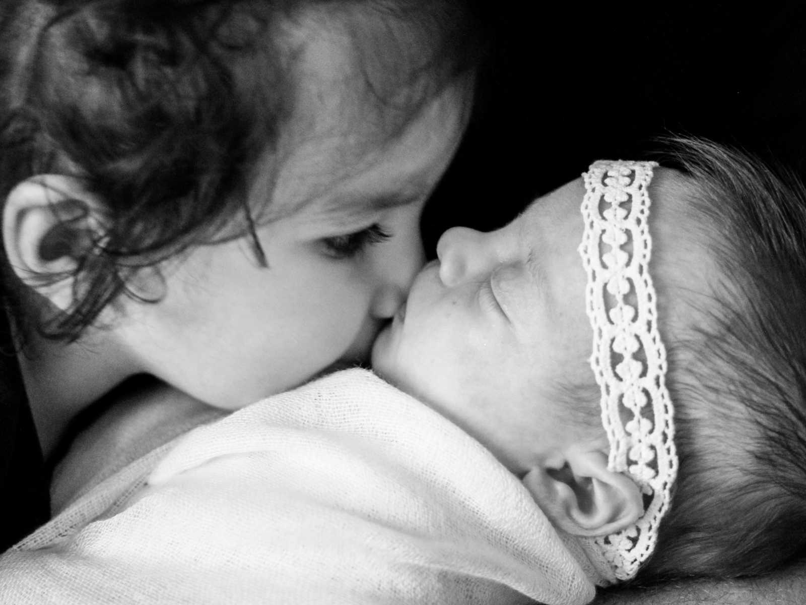 Adopted first child kisses newborn sister on the chin