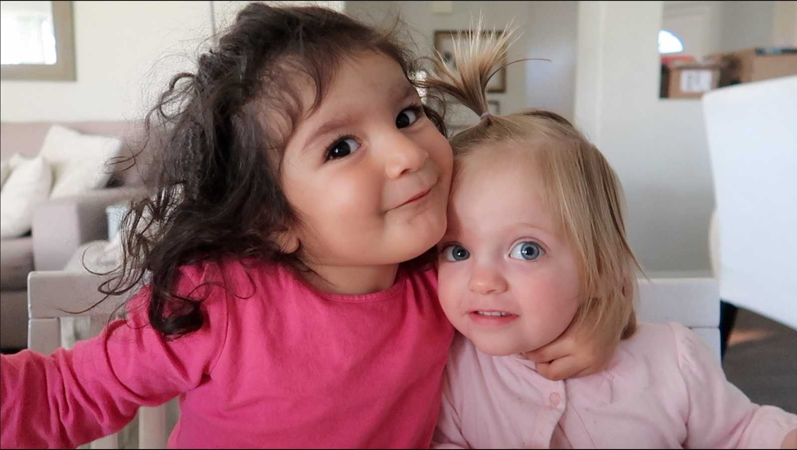 Adopted older sister smiles with arm around younger sister