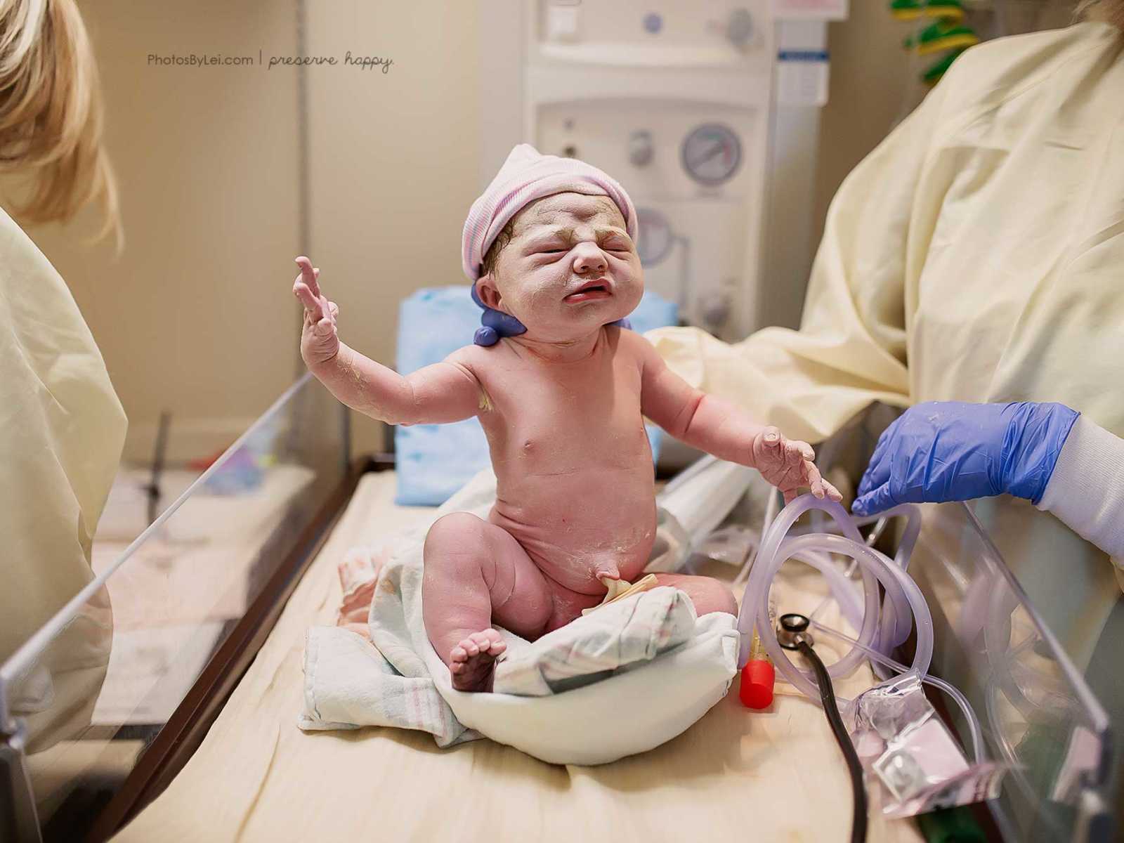 Nurse holds up newborn baby who was covered in amniotic fluid