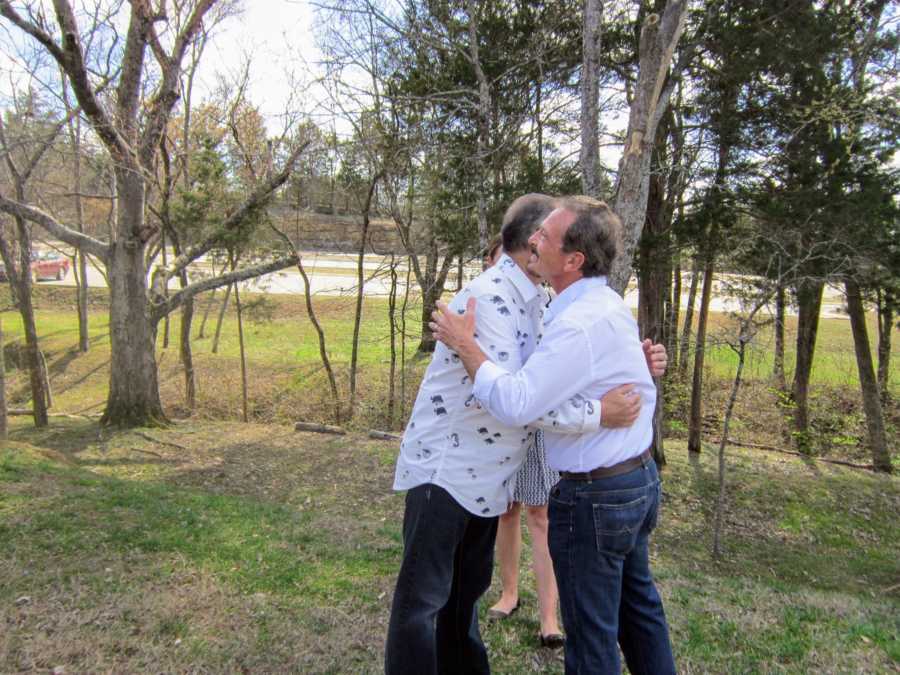 Men hug at their wedding in yard