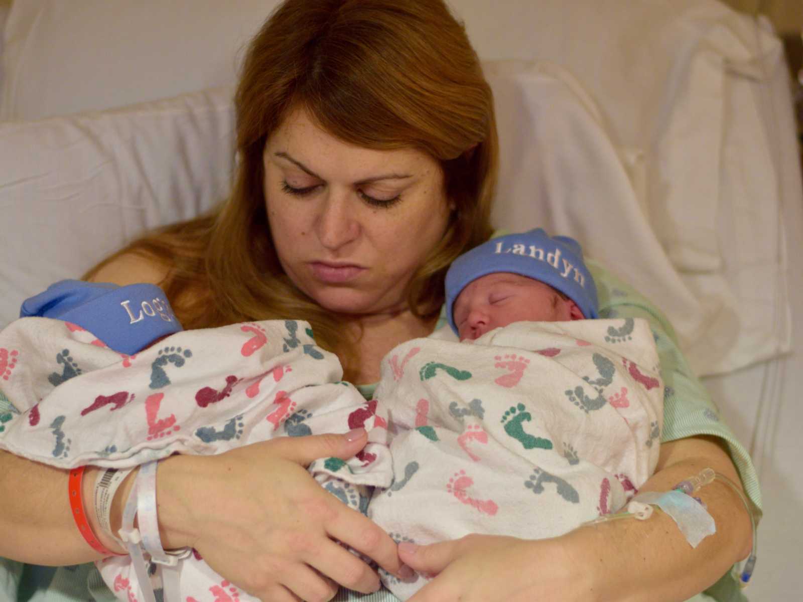 Mother holds new born twins in hospital bed that were conceived through IVF
