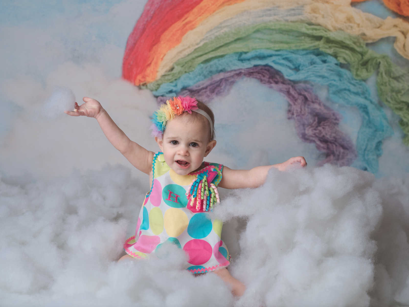 IVF baby as a toddler smiling in rainbow backdrop