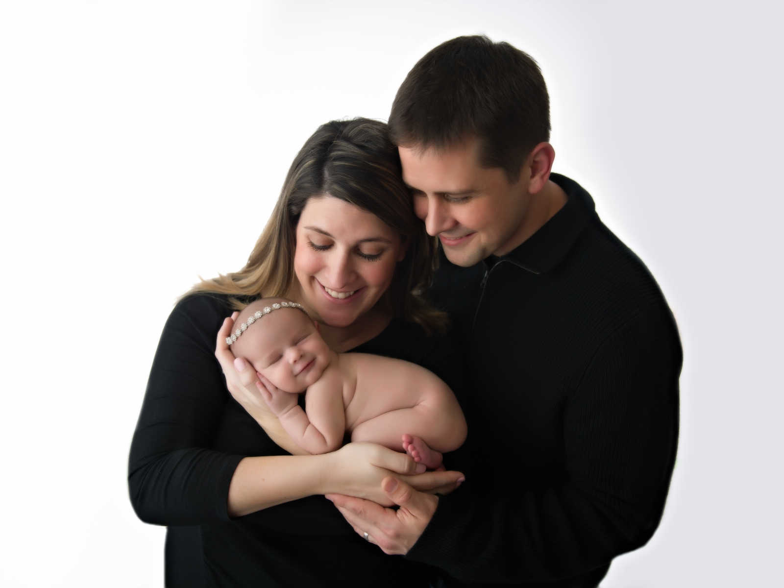 Husband and wife hold naked newborn in their arms 