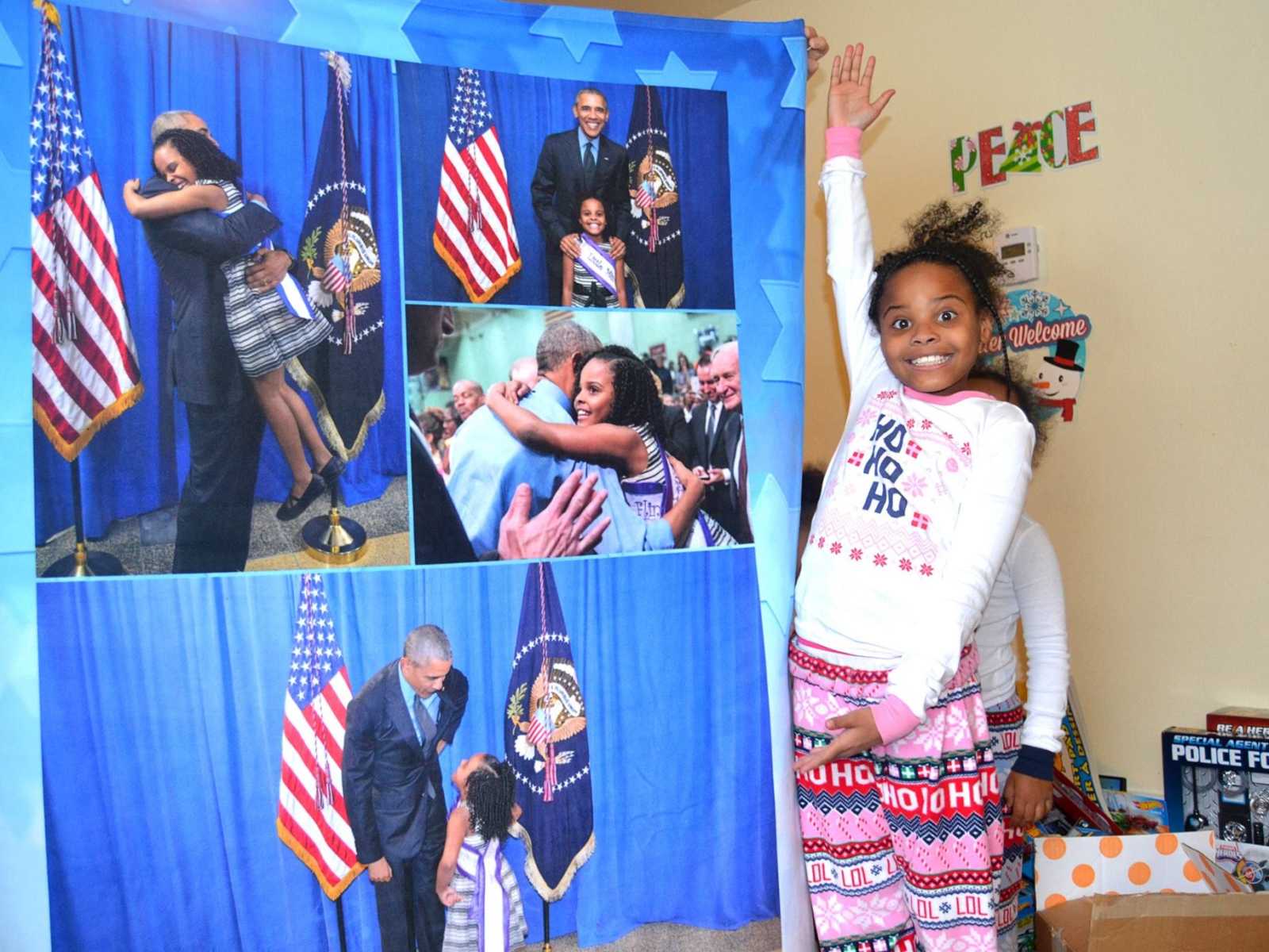 Little girl from Flint smiles and presents poster that contains a collage of her with Barack Obama