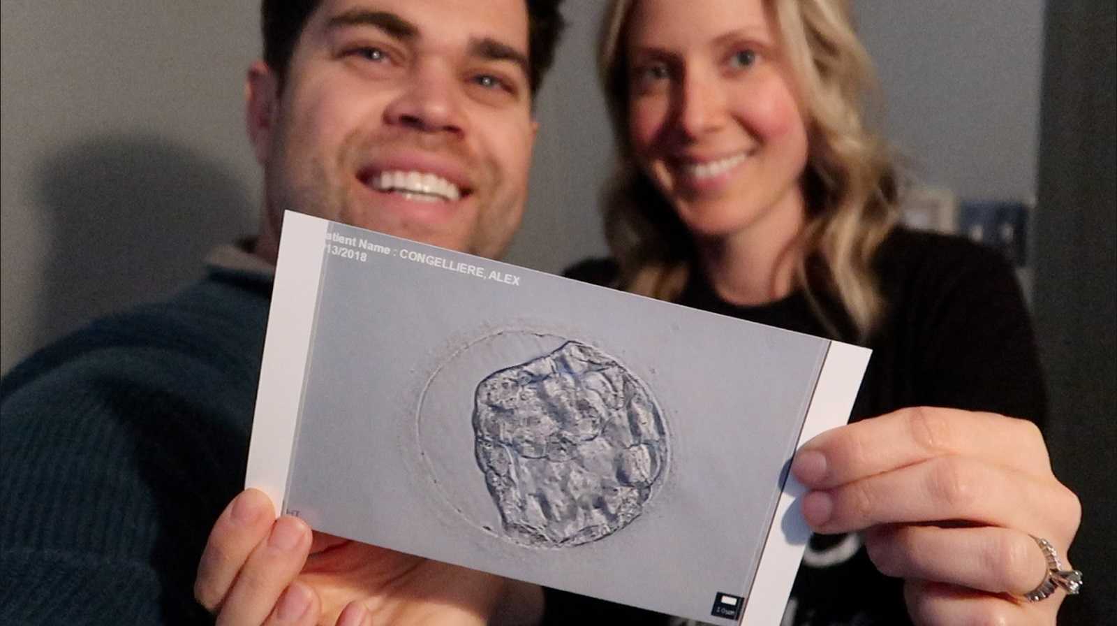 Husband and wife holding up sonogram of IVF baby