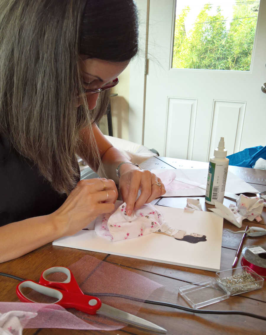 Woman making paper doll dress from baby onesie