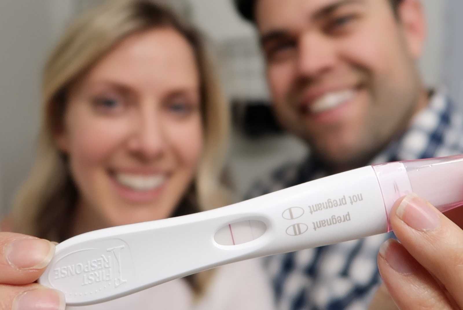 Husband and wife holding up pregnancy test that indicated pregnancy