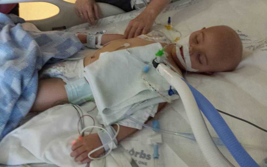 Boy with leukemia lying in hospital bed with oxygen and other wires attached to him