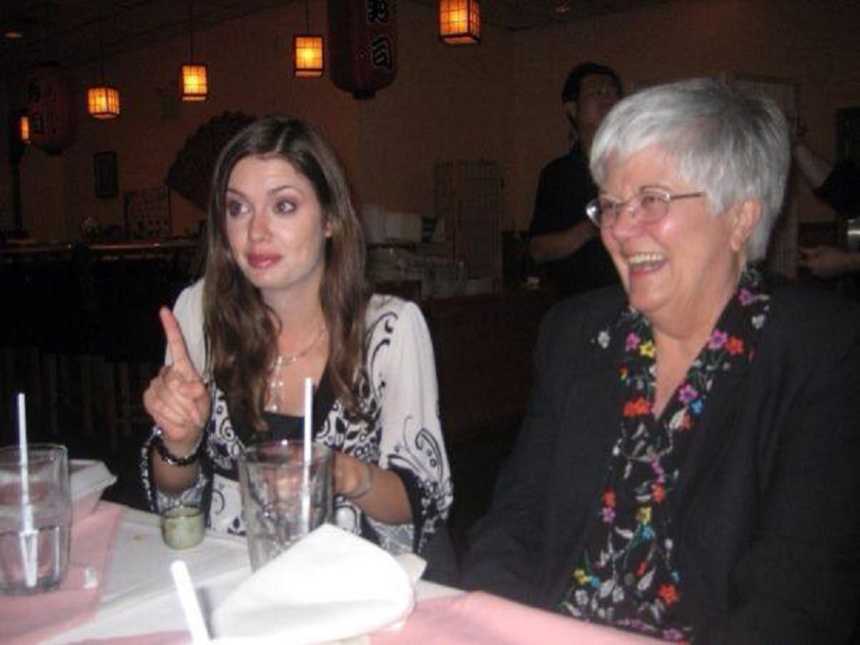 Woman with small cell cancer laughing at dinner table next to granddaughter
