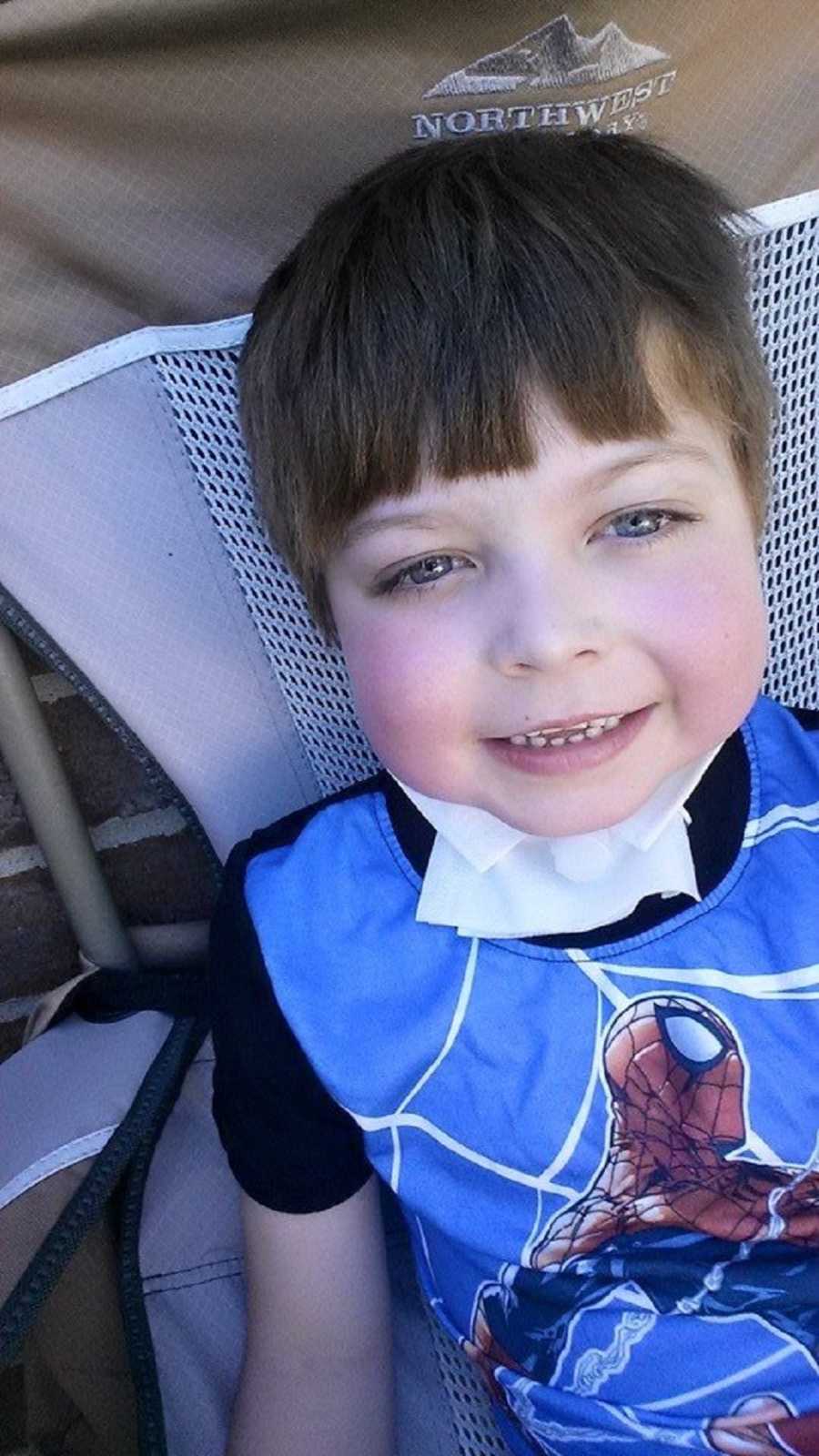 Young boy sitting in chair smiling recovering from life threatening strep throat