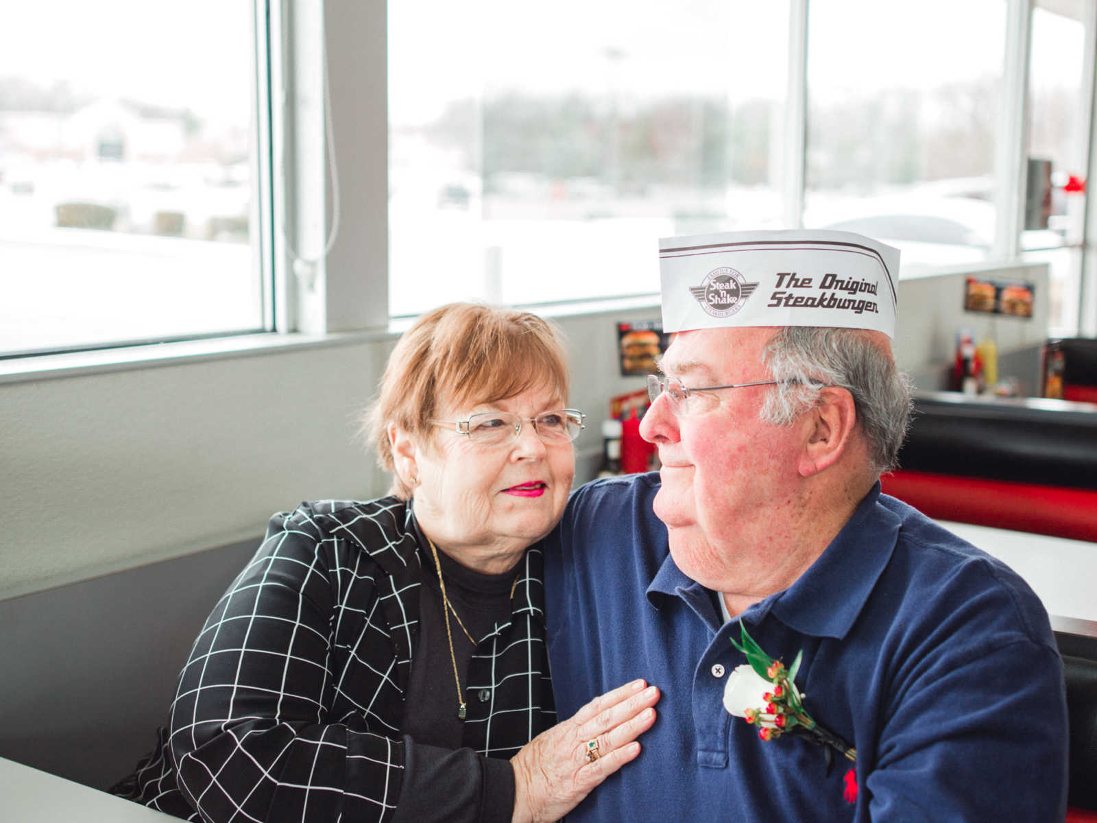 Husband and wife sit in Steak 'n Shake booth where they met in 1962 staring into each others eyes