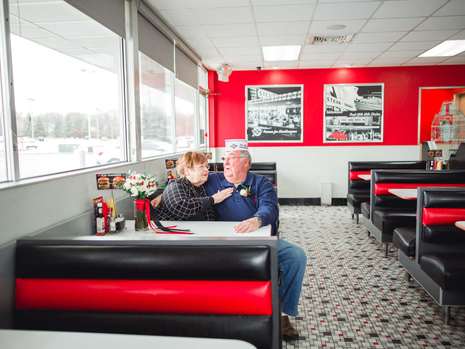 Husband sits with arm around his wife in Steak 'n Shake booth where they met in 1962