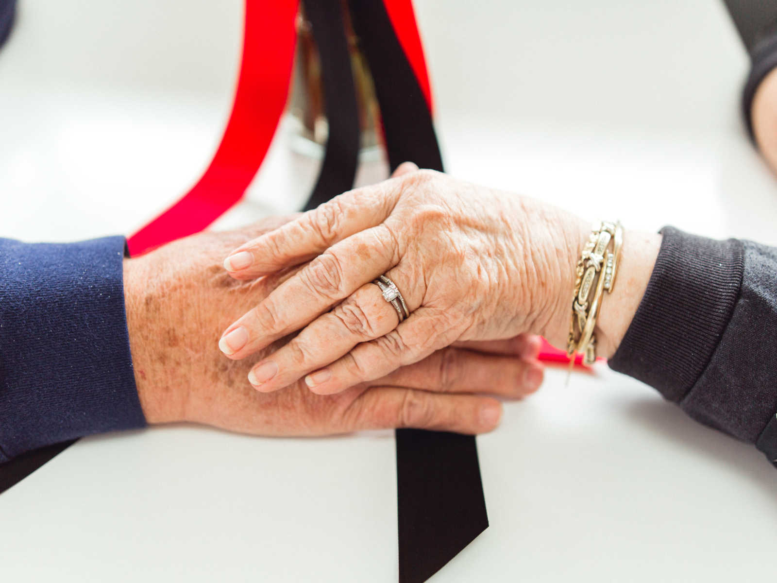 Close up of husband and wife holding hands over Steak 'n Shake table where they met in 1962