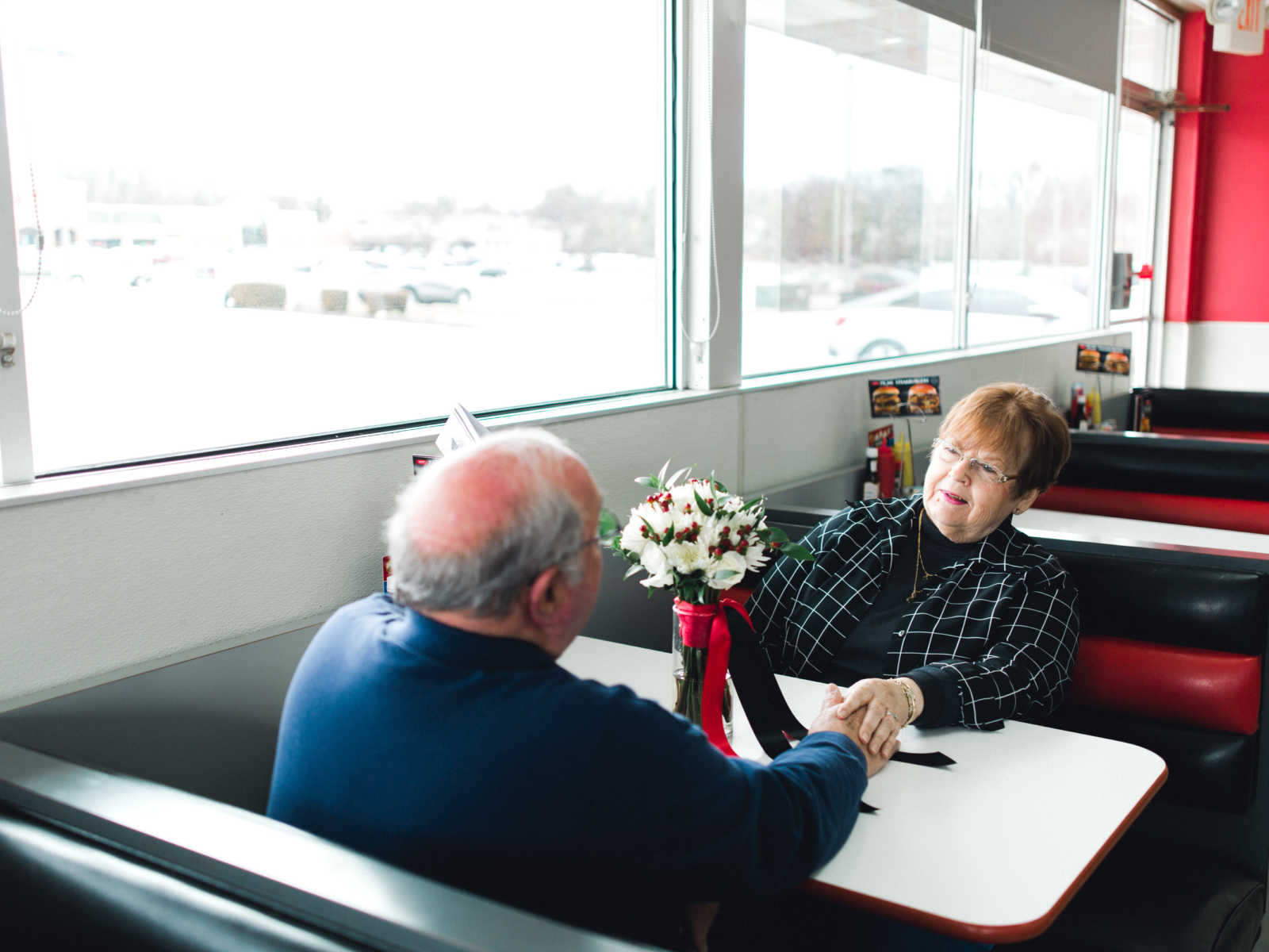 Husband and wife hold hands across Steak 'n Shake booth where they met in 1962