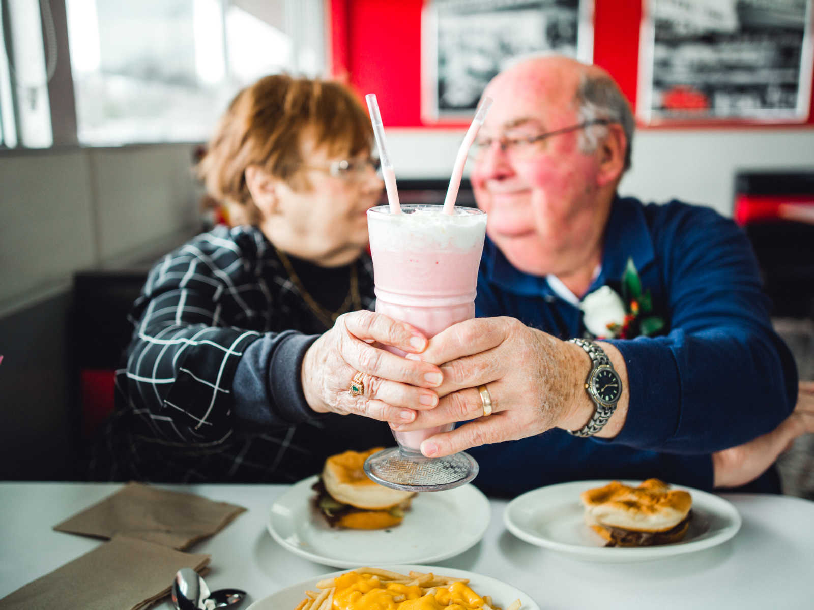 Husband and wife who met at Steak 'n Shake in 1962 smile as they hold up the milkshake they are sharing in air