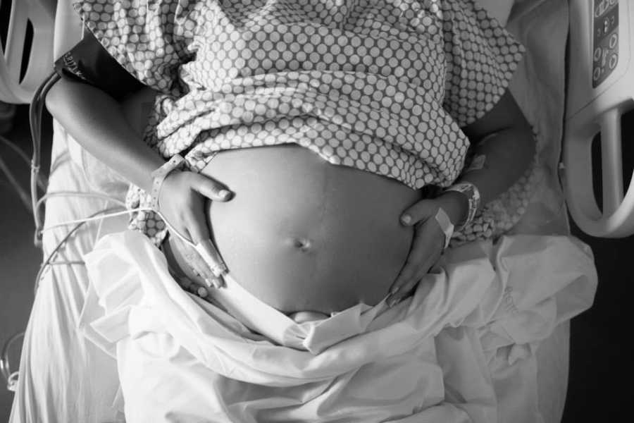 Aerial view of pregnant woman holding stomach in hospital bed