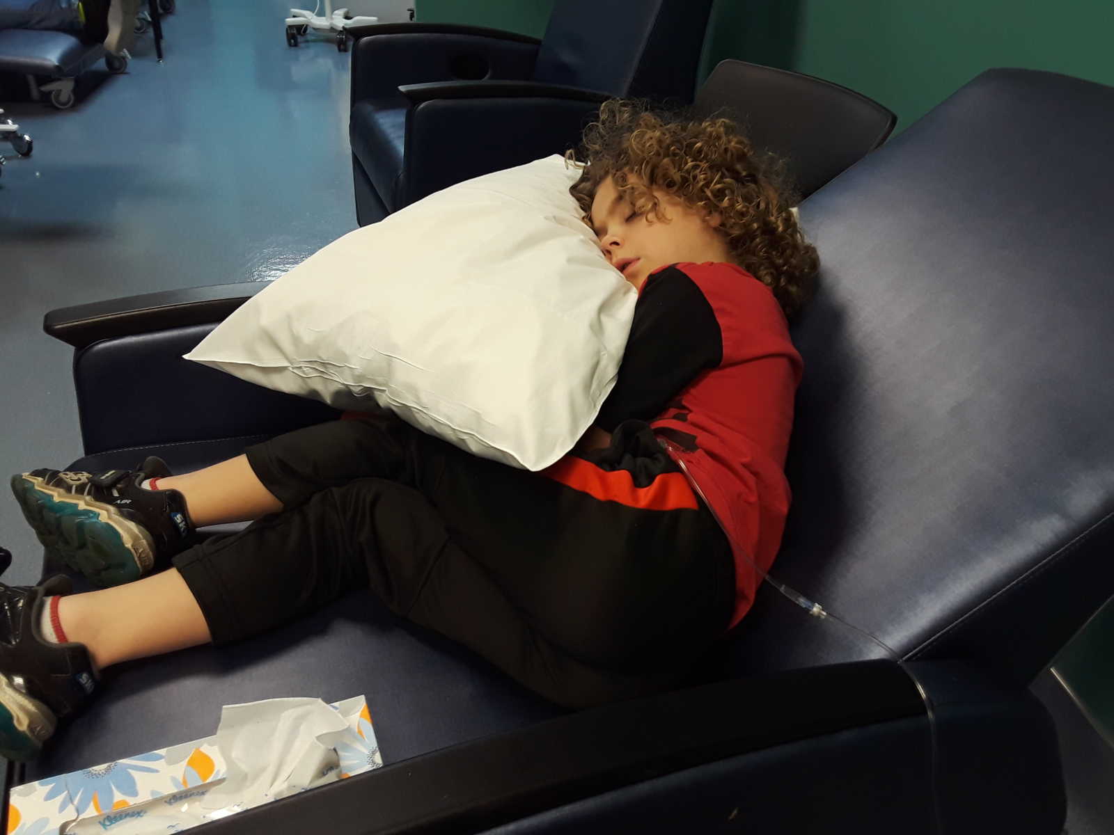 Boy with leukemia sleeping in blue recliner at hospital 