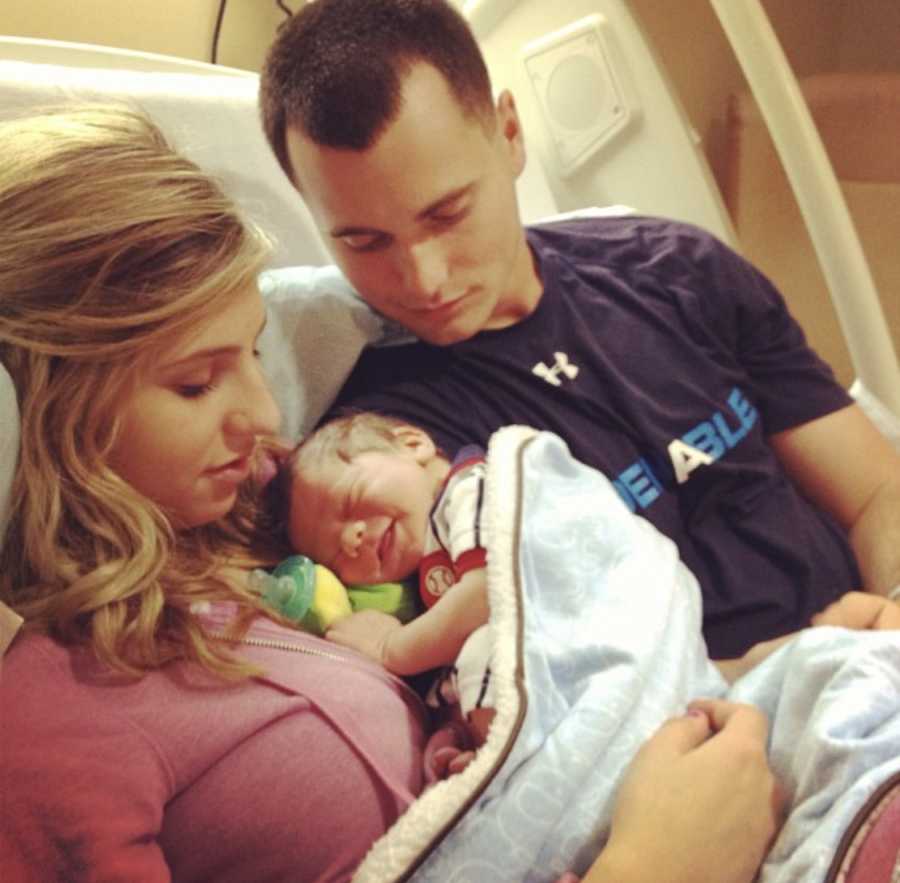 Mother and father sit in hospital bed looking at newborn son who they will put up for adoption