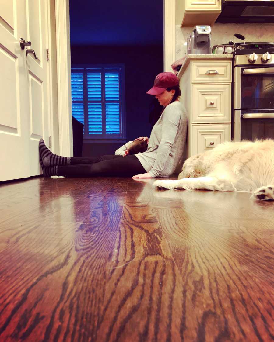 Foster mom sitting on kitchen floor with foster son who cries in her lap