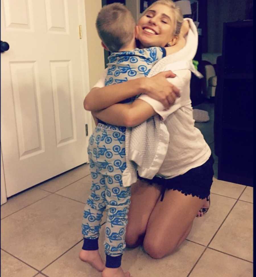 Mother kneels on kitchen floor hugging son