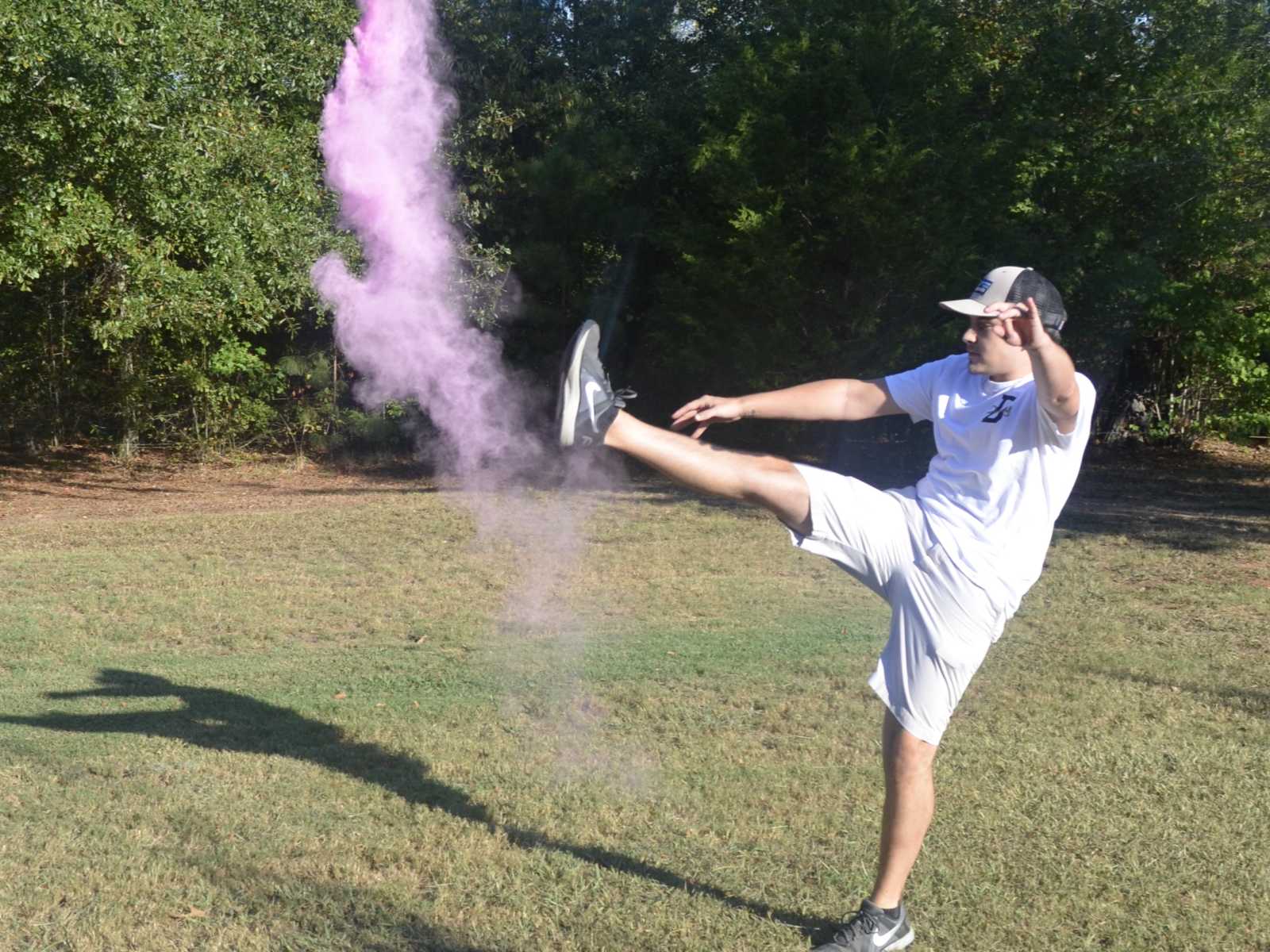 Man kicks the air full of pink smoke at gender reveal