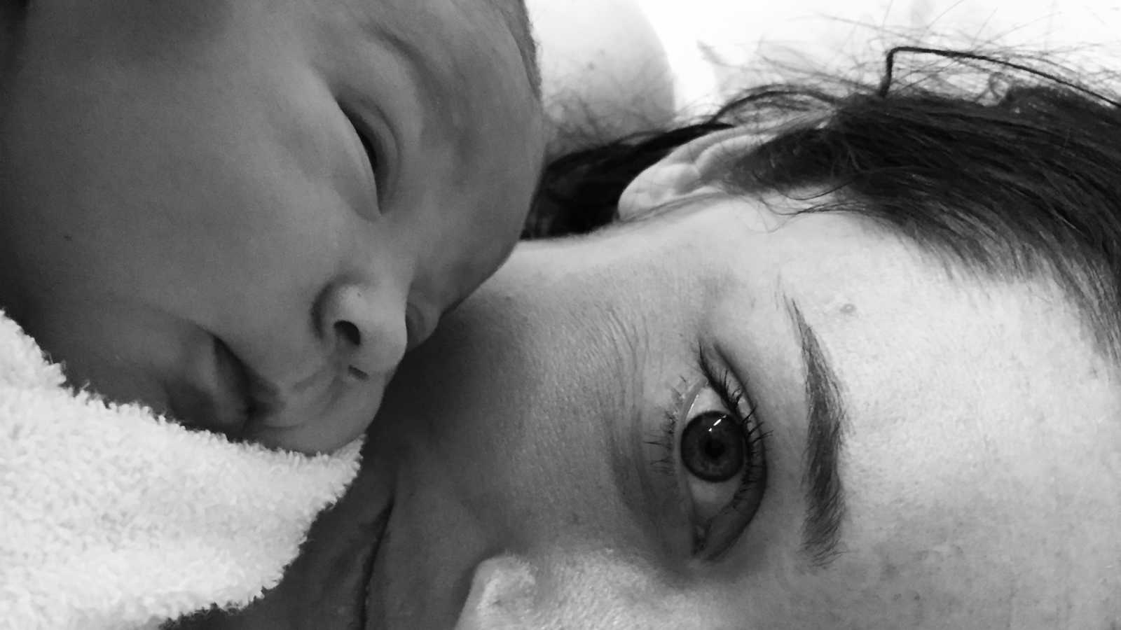 Woman who had c-section lies with eyes open while baby sleeps on her