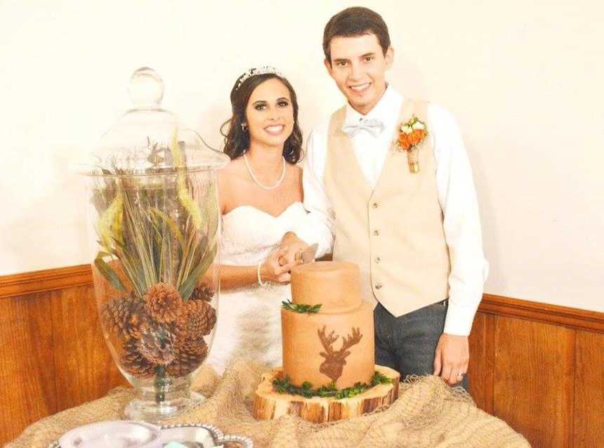 Bride and groom cut wedding cake at reception
