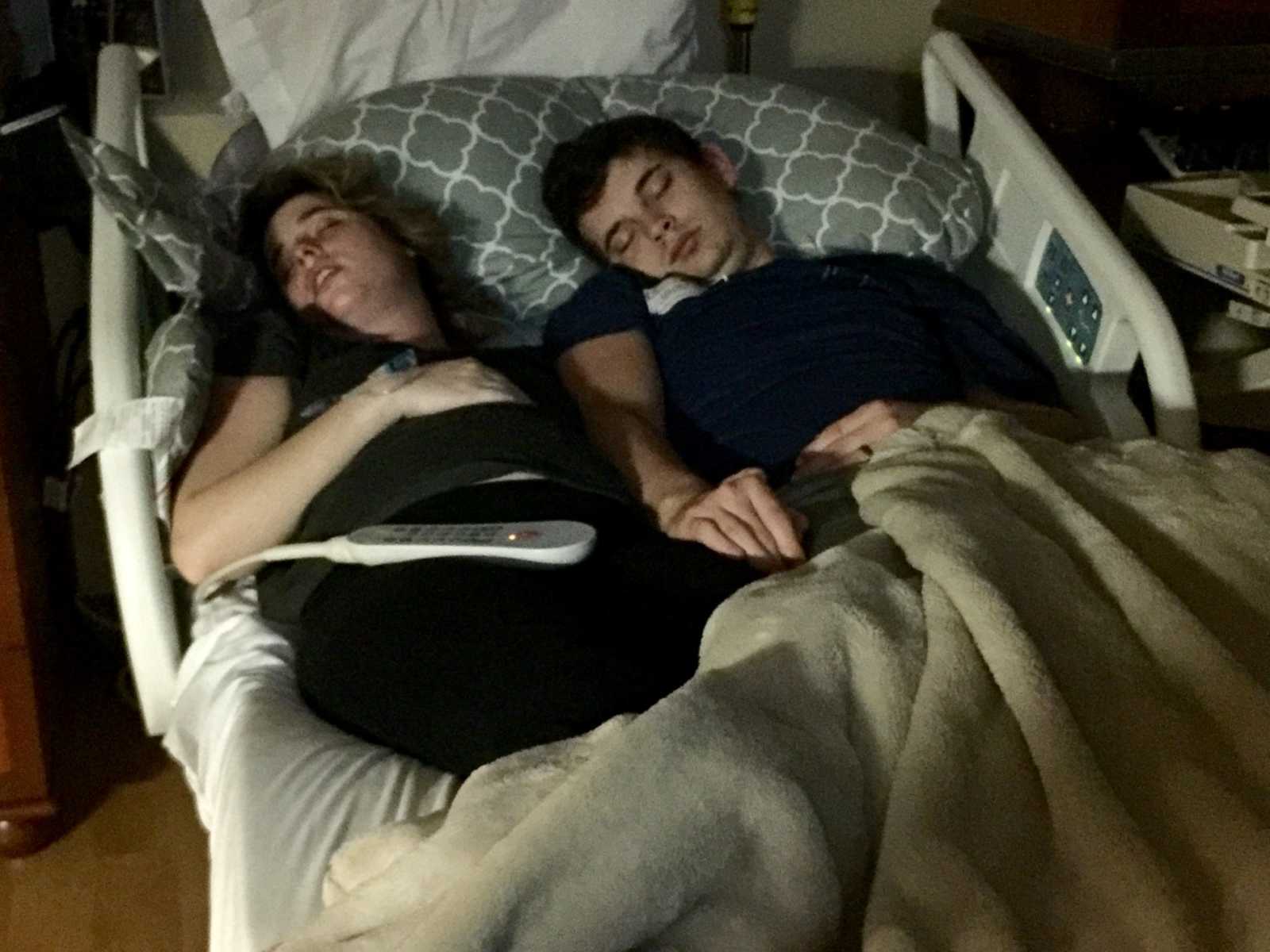Pregnant wife asleep in hospital bed next to husband