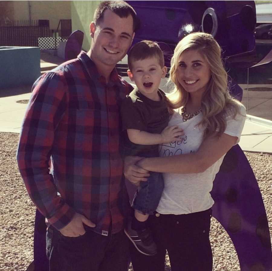 Mother stands holding son next to husband