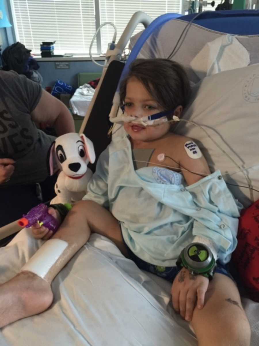 Young boy sitting up in hospital bed with oxygen up his nose recovering from life threatening strep throat