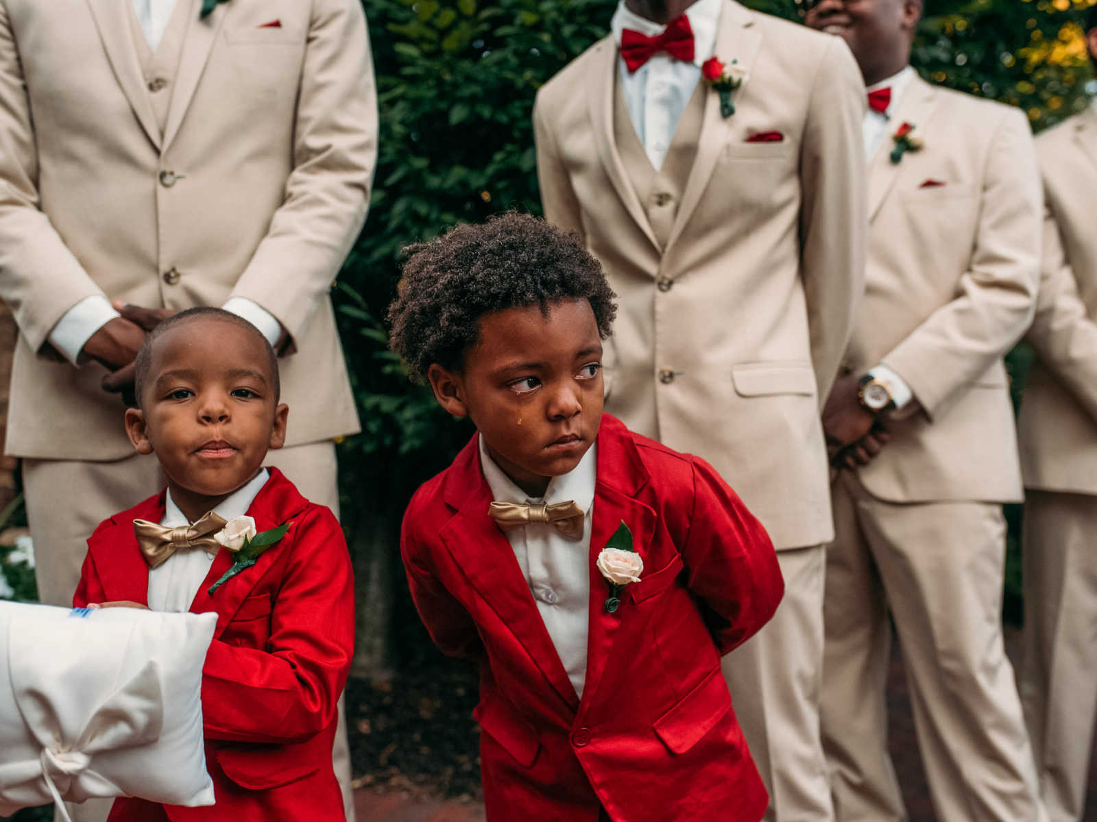 Young boy in red suit cries while mom walks down the aisle